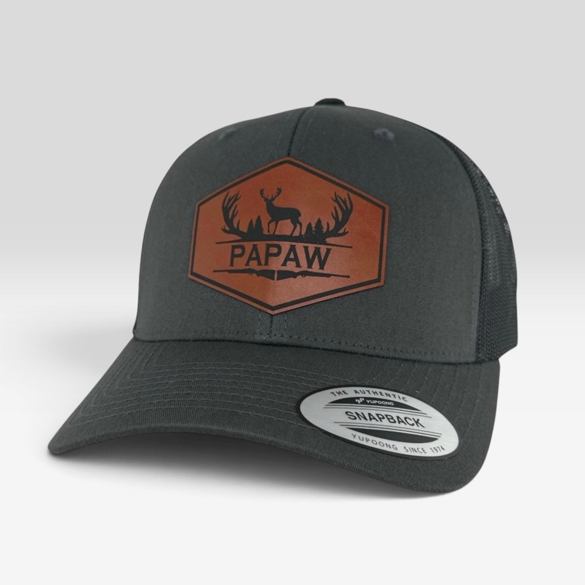 A dark gray snapback trucker hat with a brown embroidered 'PAPAW' deer logo on the front, shown on a light gray background.